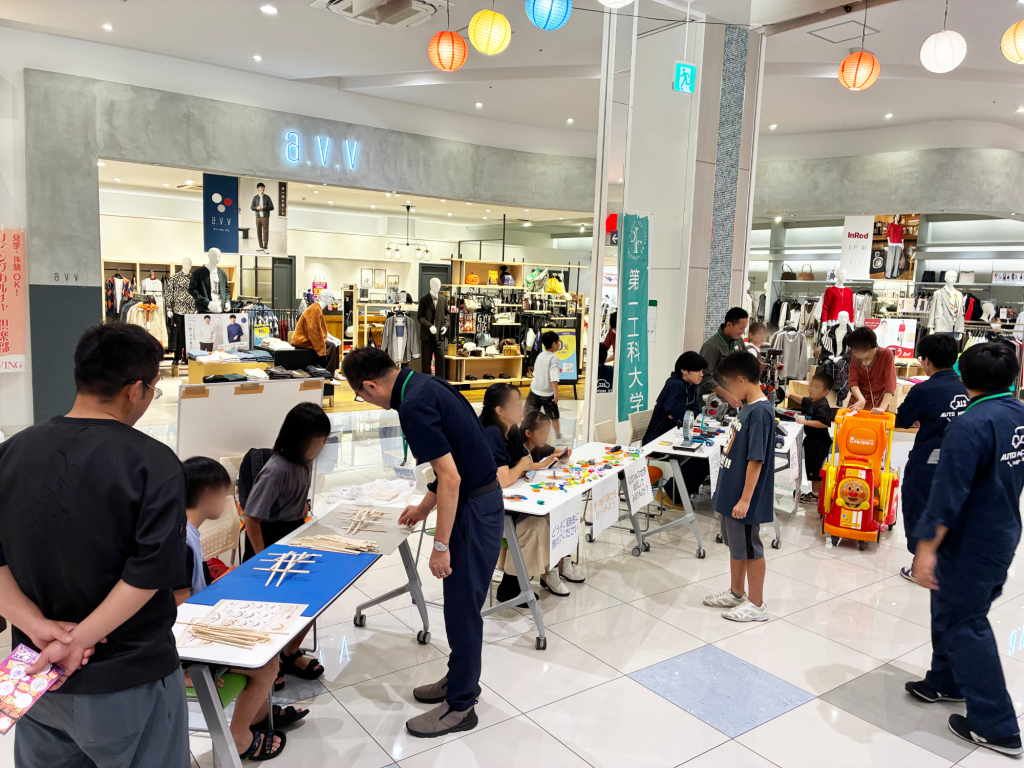 イチフェスの第一工科大学ブースで、来場者が割り箸を使った橋づくりや展示を体験する様子